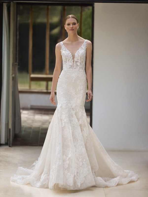 BLAIA Wedding Dress Pronovias collection 2026 | Boutique ParisThis mermaid-style wedding dress in Chantilly lace enhances the figure with refined elegance. The deep neckline flatters the bust, while slender straps and an open back add a feminine touch. The fitted silhouette flows into a flared skirt with a graceful train, offering a timeless and sophisticated bridal look. BLAIA Wedding Dress Pronovias collection 2026 | Boutique Paris